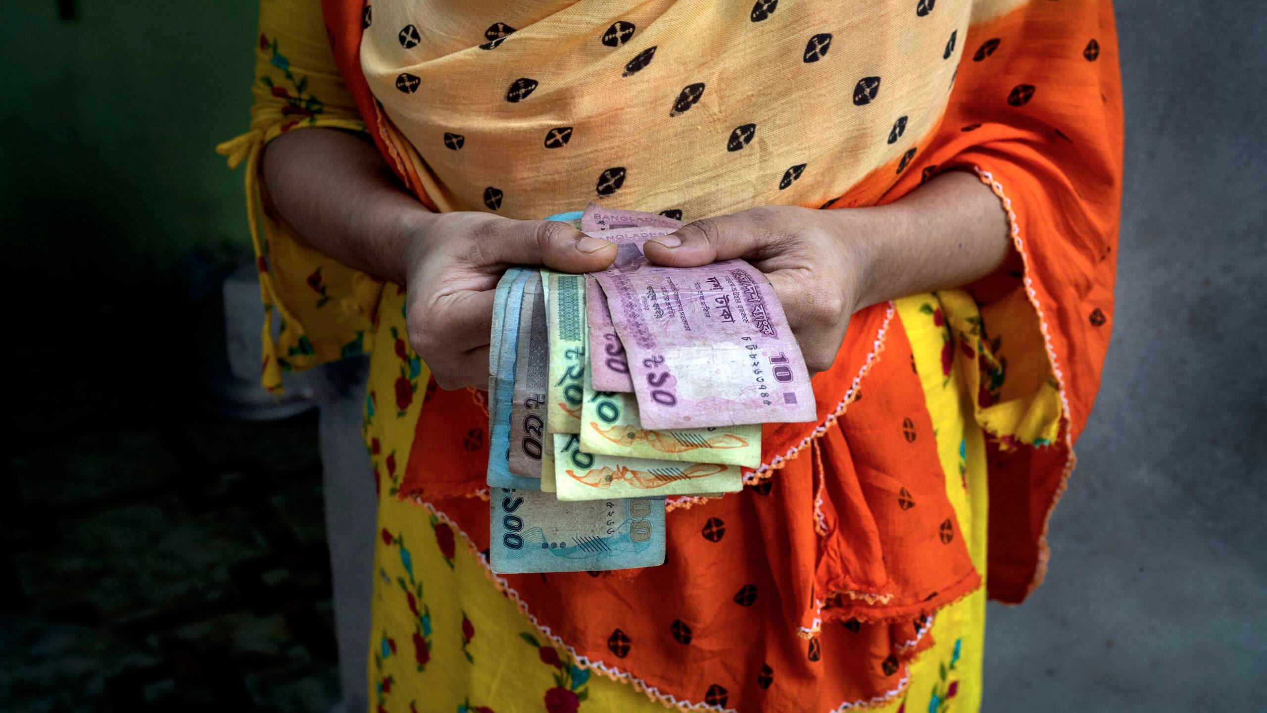 Una mujer con unos cuantos billetes entre las manos, en Bangladesh.